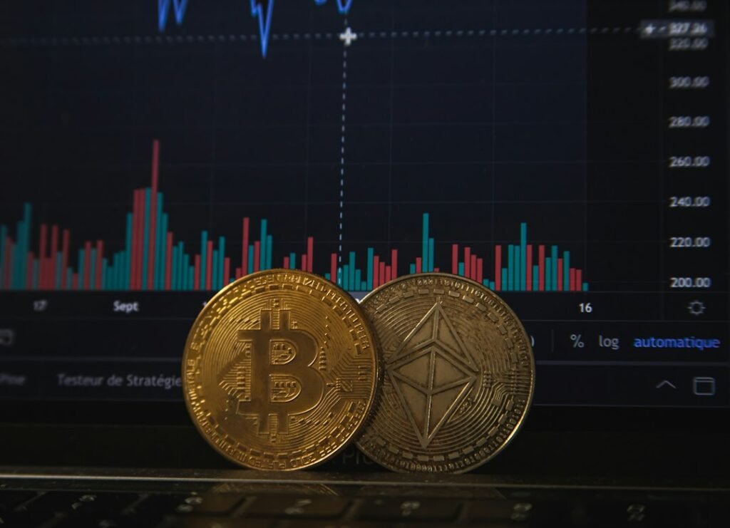 Bitcoin and Ethereum coins on a laptop keyboard in front of a trading chart