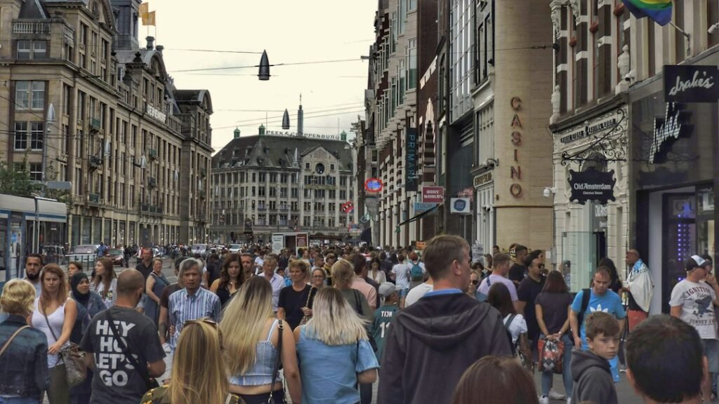 Crowd of people walking down a city street between tall buildings