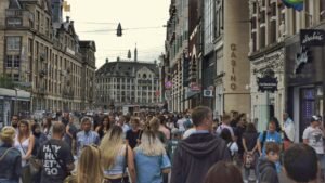 Crowd of people walking down a city street between tall buildings