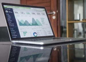 Laptop showing data analytics charts on a glass table