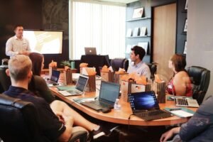 Manager presenting to a team seated at a table with laptops