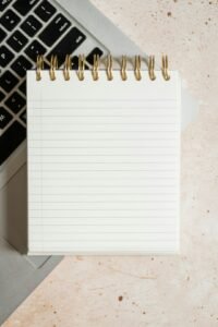 Notepad on top of a laptop next to a keyboard