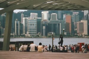 People relaxing by a statue overlooking a city skyline