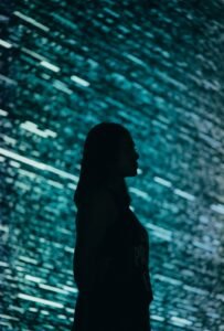 Person standing before a large digital screen, symbolizing humanity's relationship with advanced AI systems