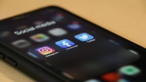 Smartphone showing social media apps on a wooden table