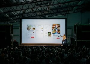 Speaker presenting slides on a large screen to an audience