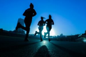 Three women running on a road at sunrise