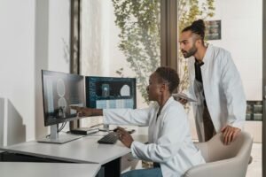 Two medical professionals reviewing a brain scan on computer monitors