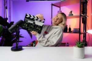 Woman holding a film clapperboard at a table