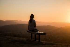 Woman sitting on a bench looking out over mountains