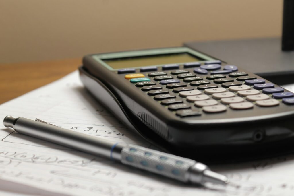 Calculator and pen on paperwork, representing AI tools for accountants and bookkeepers