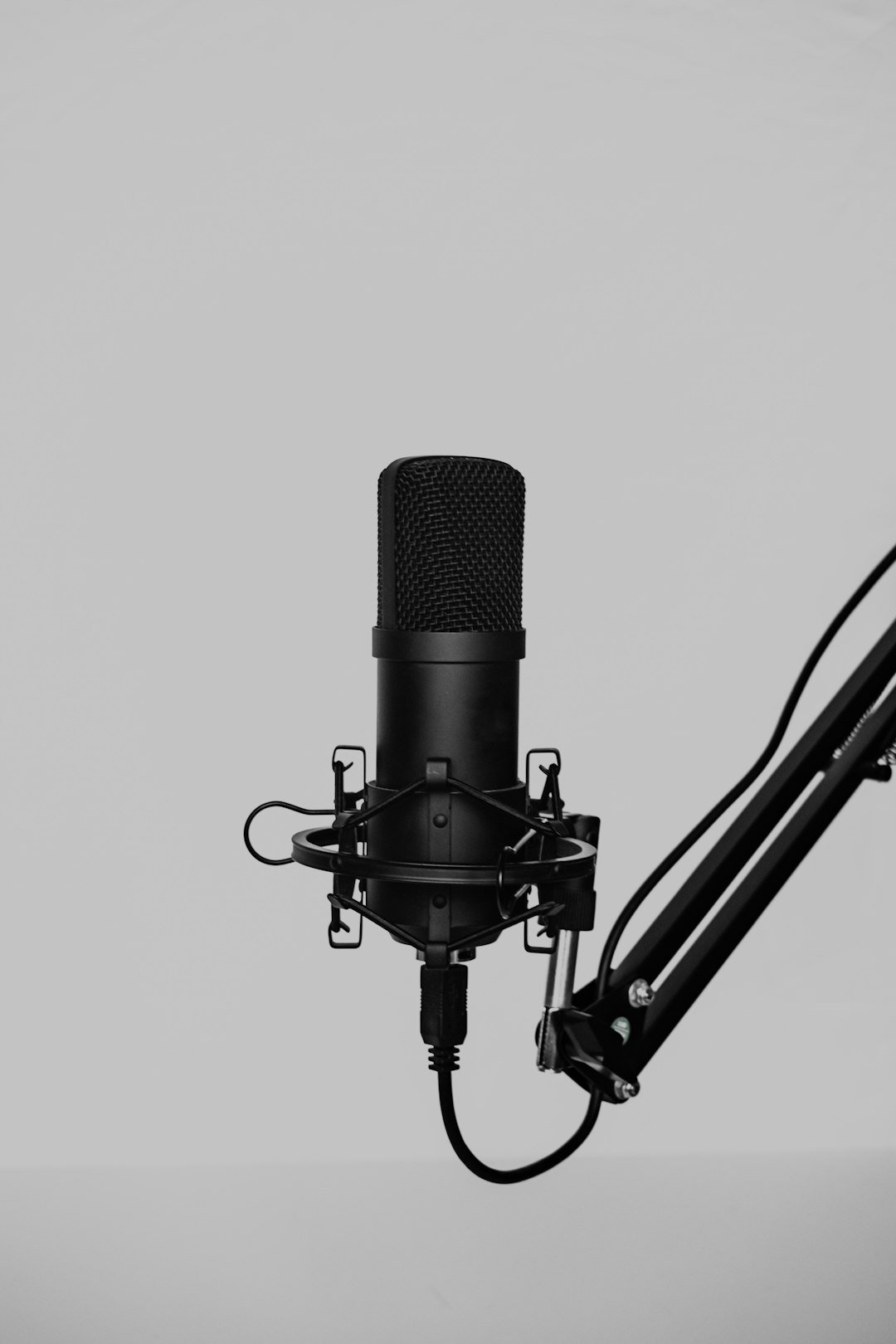 Condenser microphone on a boom arm, the kind of setup used to record a short sample for ElevenLabs voice cloning