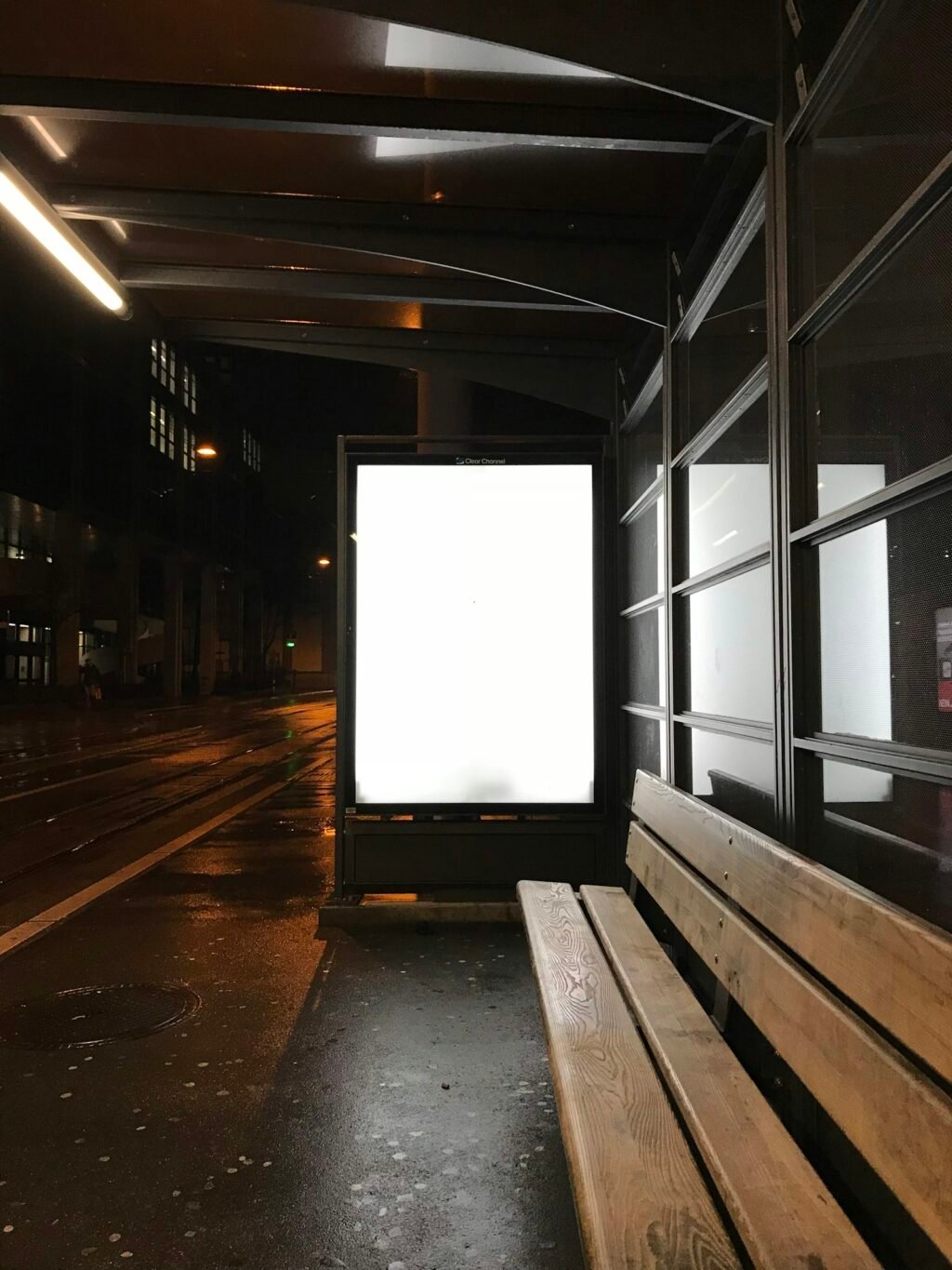 Glowing blank advertising billboard at a bus stop at night, representing ChatGPT ads for advertisers