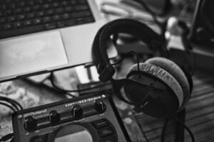 Headphones on a music sampler next to a laptop, illustrating how to use Suno AI to make songs