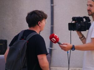 Person being interviewed with a microphone and camera, a typical job for the best AI transcription software