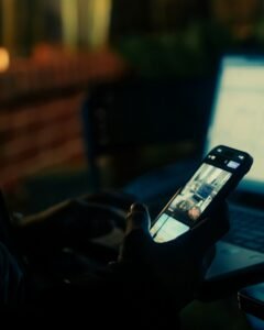 Person using a smartphone and laptop at night, illustrating X Subscription pricing for Grok and Cursor