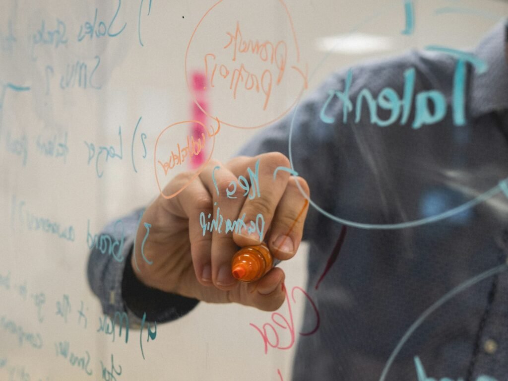 Person writing a plan on a glass whiteboard, representing choosing AI tools for marketing