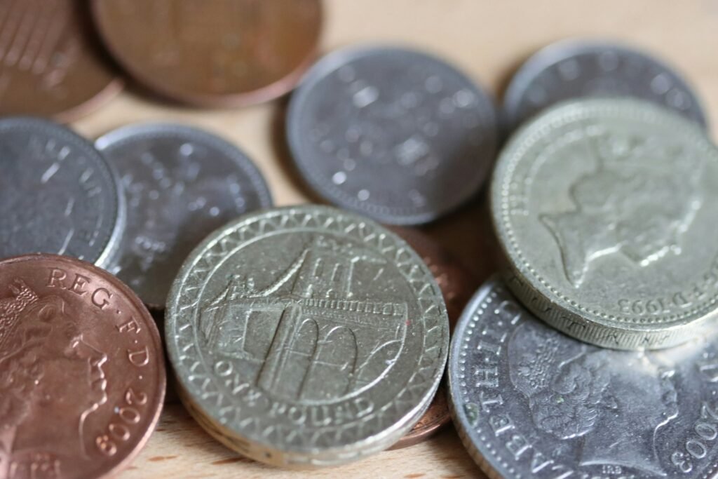 Pile of British coins on a wooden table, illustrating Gemini pricing and Google AI plan costs in the UK